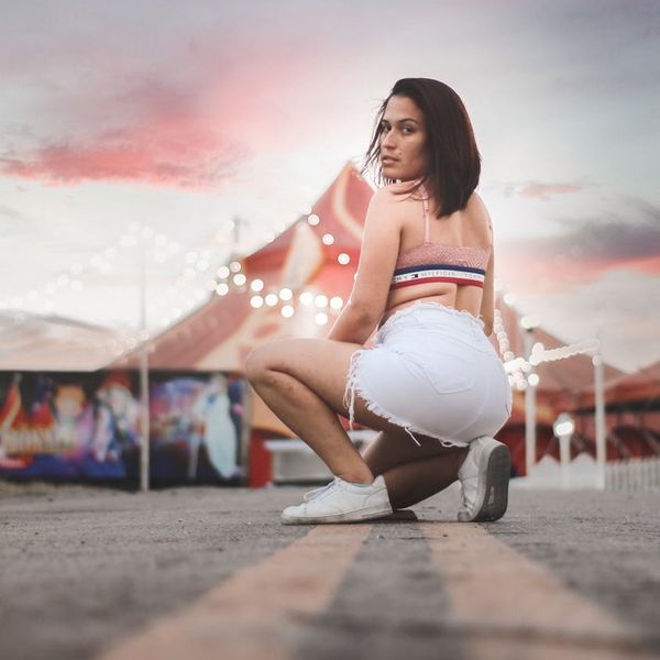 Silhouette of a person in a dynamic yoga flow against a pink-hued backdrop.