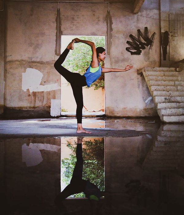 Woman in a calm yoga pose in a dark room with pink light.